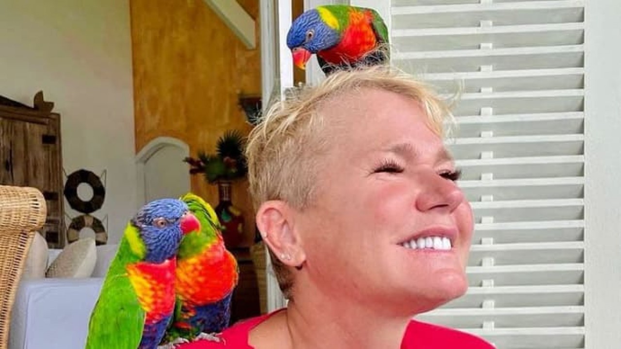 Xuxa com seus passarinhos em casa sorrindo