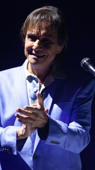 Roberto Carlos de terno azul batendo palmas em palco